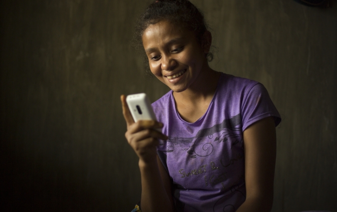 Ela, in Indonesia, looks at her mobile phone.