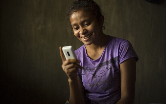 Ela, in Indonesia, looks at her mobile phone.