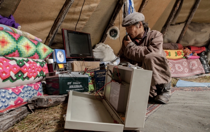 Mongolian man uses his phone in his ger, a photo taken by Sarah O Connell